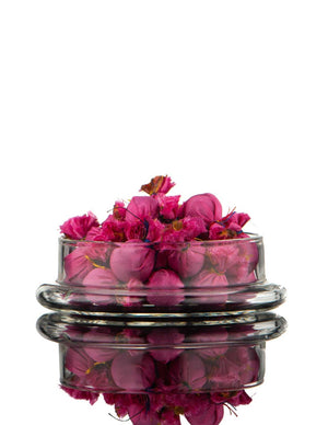 Glass container with pink pills on a white background